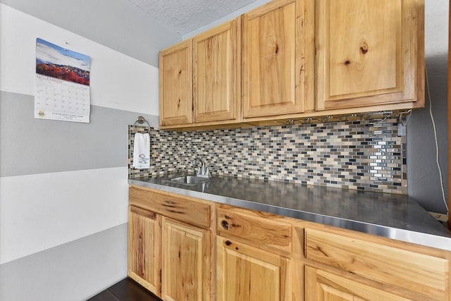 kitchen featuring stainless steel counters, a textured ceiling, light brown cabinets, sink, and decorative backsplash