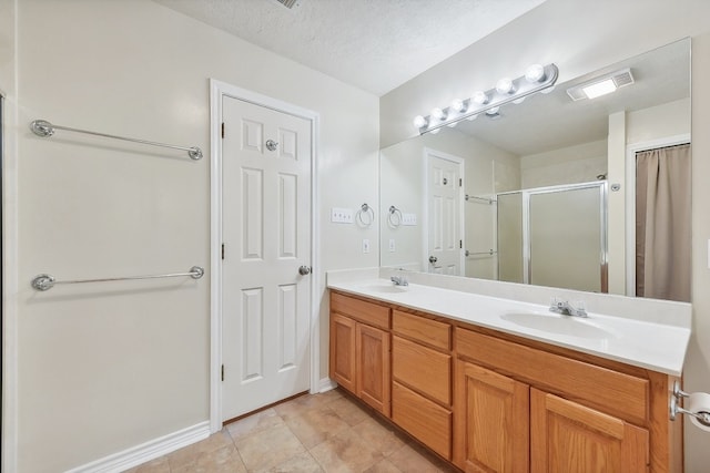 bathroom with tile patterned flooring, vanity, a textured ceiling, and a shower with door