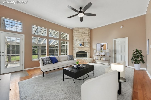 living room featuring hardwood / wood-style floors, a fireplace, ceiling fan, and crown molding