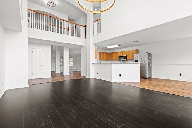 unfurnished living room with a notable chandelier, hardwood / wood-style flooring, and a towering ceiling