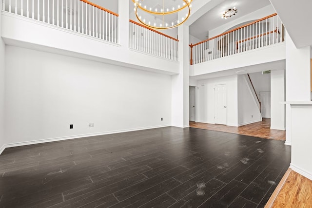 unfurnished living room featuring a high ceiling, dark hardwood / wood-style floors, and an inviting chandelier