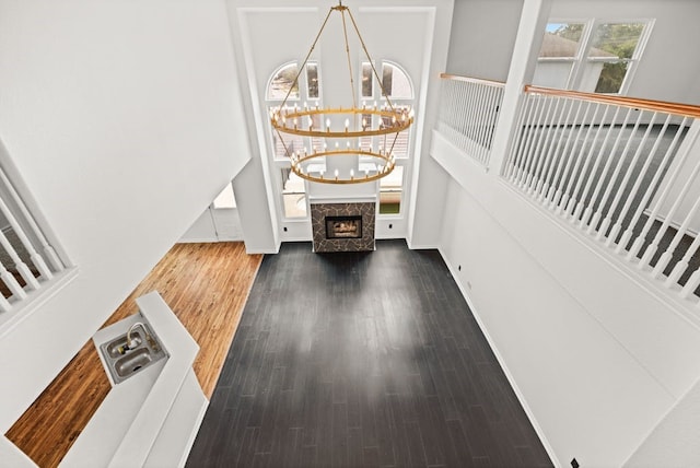 entryway featuring dark wood-type flooring, a chandelier, and a high end fireplace