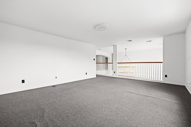 carpeted spare room featuring an inviting chandelier