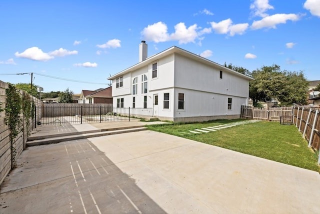 back of house featuring a lawn and a patio area