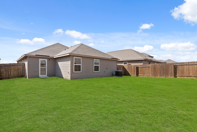 rear view of house with central AC and a yard