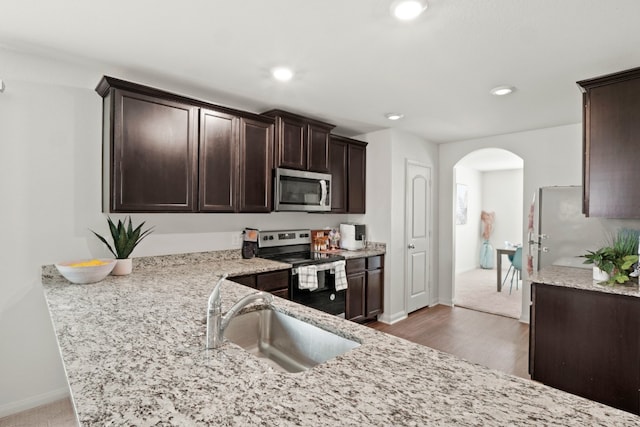 kitchen featuring appliances with stainless steel finishes, dark wood-type flooring, sink, and light stone countertops