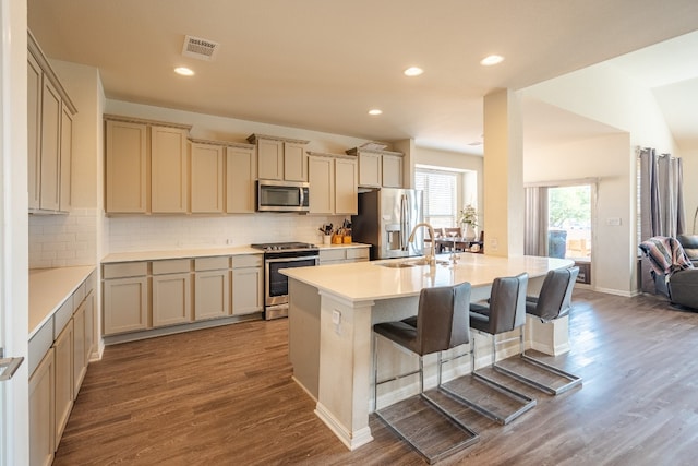 kitchen featuring stainless steel appliances, light hardwood / wood-style floors, sink, tasteful backsplash, and a kitchen bar