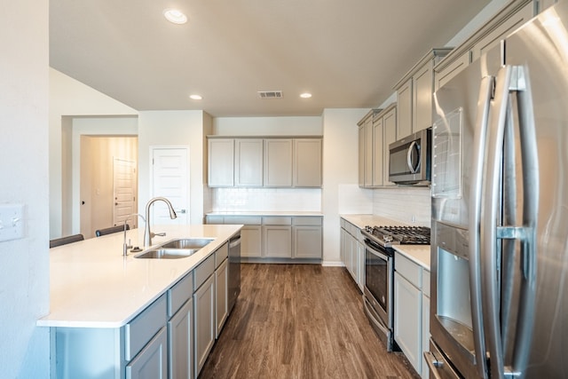 kitchen with gray cabinets, stainless steel appliances, sink, and tasteful backsplash