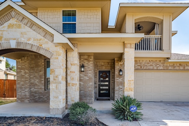 view of exterior entry featuring a garage and a balcony