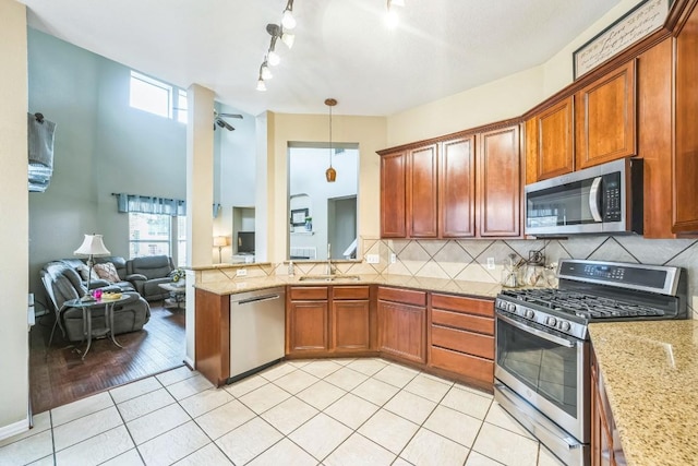 kitchen featuring hanging light fixtures, appliances with stainless steel finishes, a healthy amount of sunlight, and decorative backsplash