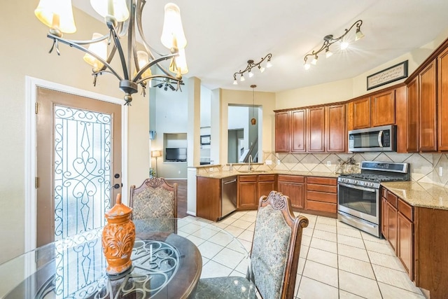 kitchen featuring sink, hanging light fixtures, light tile patterned floors, stainless steel appliances, and decorative backsplash