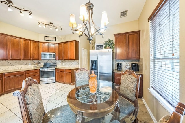 kitchen featuring decorative backsplash, hanging light fixtures, a notable chandelier, stainless steel appliances, and plenty of natural light