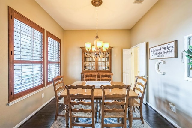 dining room with dark wood-type flooring and a chandelier