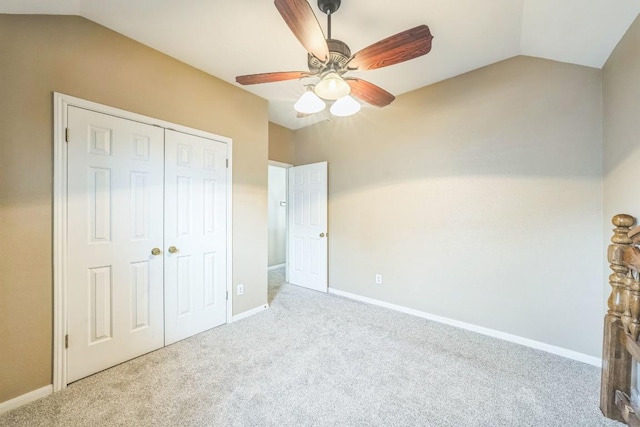 unfurnished bedroom featuring light carpet, vaulted ceiling, a closet, and ceiling fan