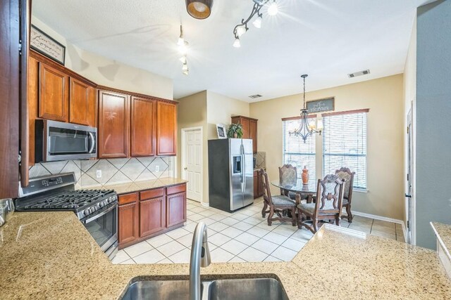 kitchen with sink, appliances with stainless steel finishes, backsplash, hanging light fixtures, and a chandelier