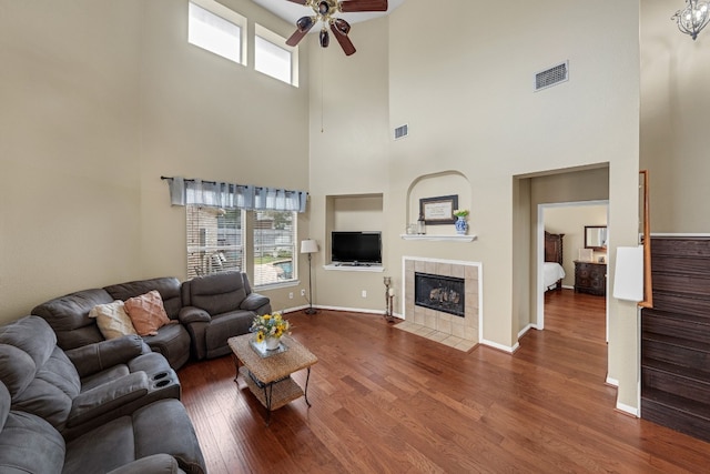 living room featuring plenty of natural light, a tile fireplace, dark hardwood / wood-style floors, and ceiling fan