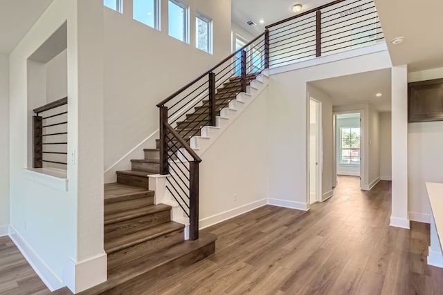 stairway featuring wood-type flooring and a towering ceiling