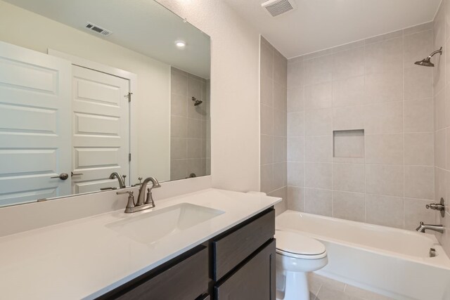 full bathroom featuring tile patterned floors, vanity, toilet, and tiled shower / bath combo