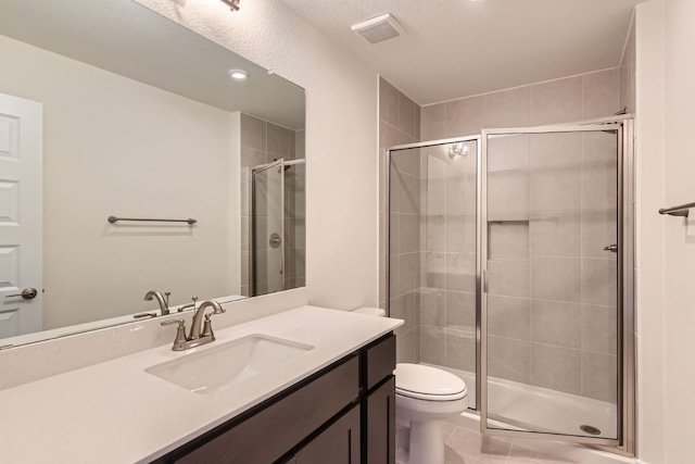 bathroom featuring tile patterned flooring, vanity, toilet, and walk in shower