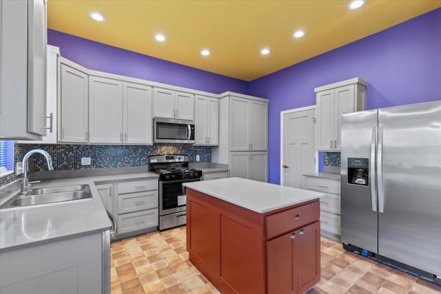 kitchen featuring stainless steel appliances, white cabinets, sink, a kitchen island, and backsplash