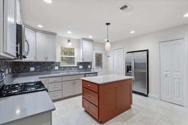 kitchen featuring sink, appliances with stainless steel finishes, decorative light fixtures, a kitchen island, and decorative backsplash