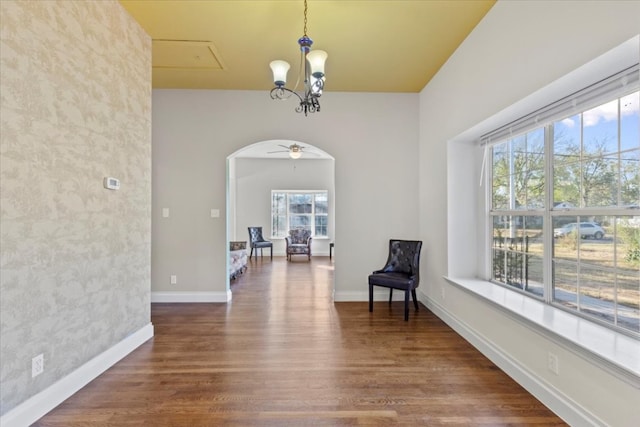 living area featuring dark wood-type flooring and ceiling fan with notable chandelier