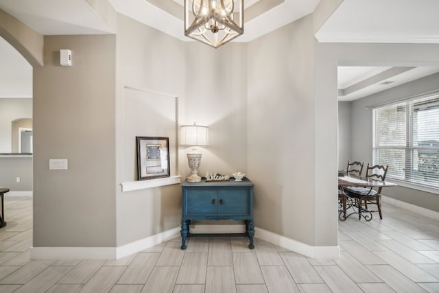 hallway featuring a chandelier and a raised ceiling