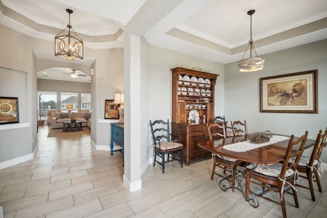 dining area with ceiling fan and a tray ceiling