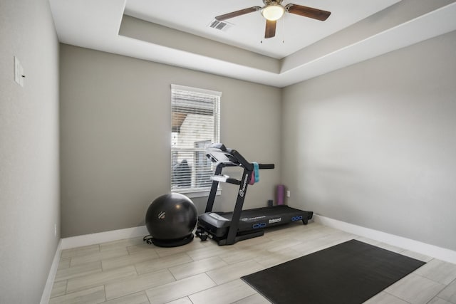 exercise area with ceiling fan and a raised ceiling