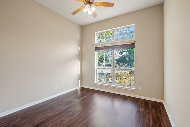 spare room featuring dark wood-style floors, ceiling fan, and baseboards