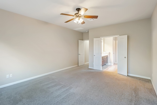 unfurnished bedroom featuring light carpet, ensuite bath, baseboards, and a ceiling fan