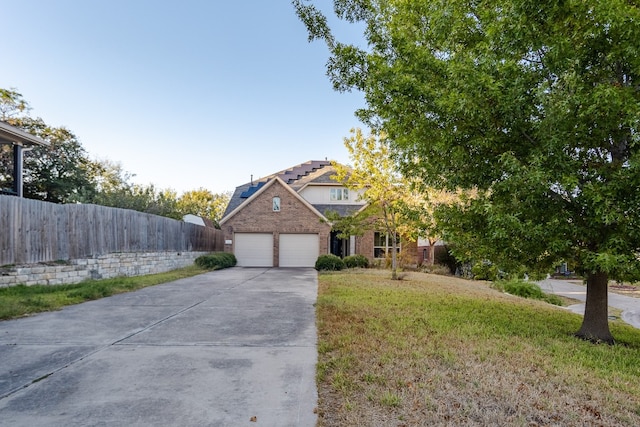 view of front of house featuring brick siding, an attached garage, a front yard, fence, and driveway