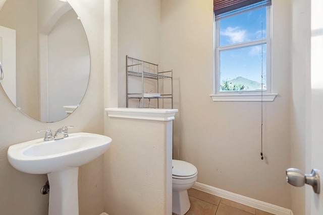 half bathroom featuring baseboards, toilet, and tile patterned floors