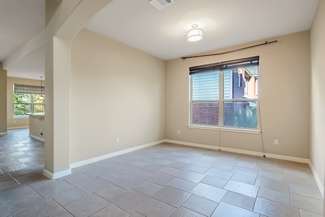 spare room with arched walkways, visible vents, and baseboards