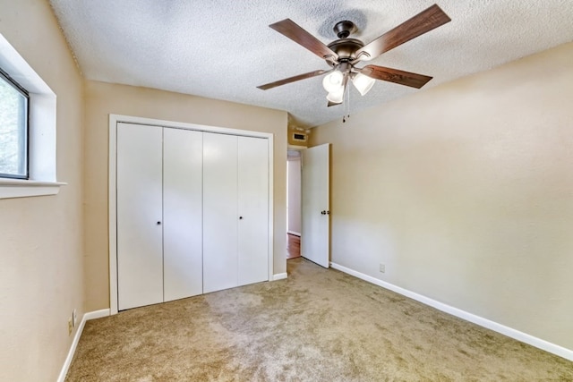 unfurnished bedroom featuring ceiling fan, light colored carpet, a closet, and a textured ceiling