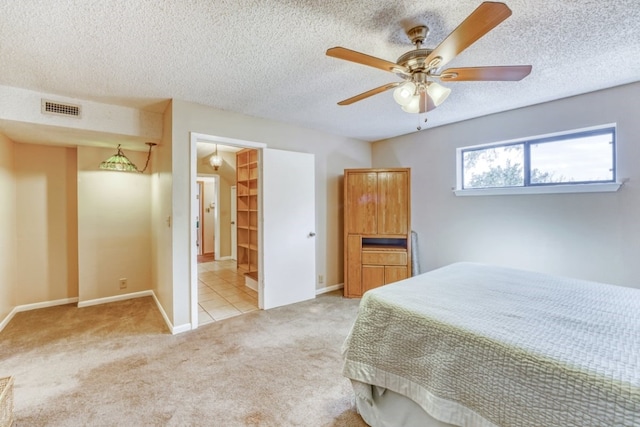 bedroom with ceiling fan, light carpet, and a textured ceiling