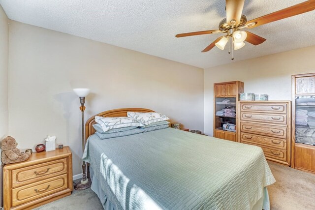 carpeted bedroom featuring ceiling fan and a textured ceiling