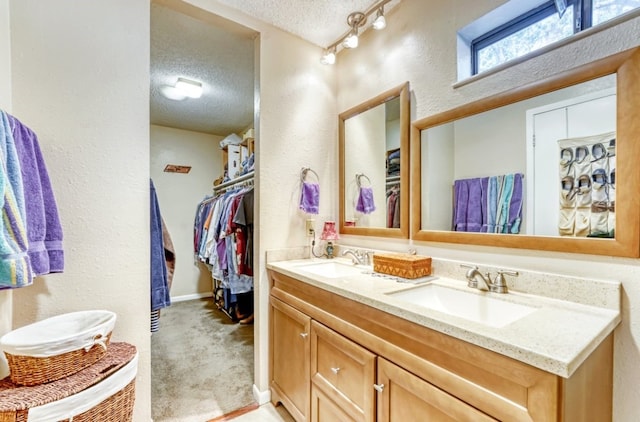 bathroom featuring vanity, rail lighting, and a textured ceiling