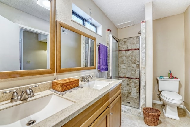 bathroom featuring a tile shower, tile patterned flooring, vanity, toilet, and a textured ceiling