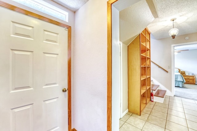 corridor featuring a textured ceiling and light tile patterned flooring