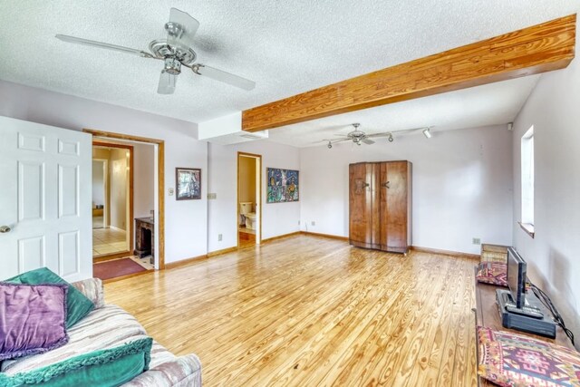 living room featuring ceiling fan, hardwood / wood-style floors, a textured ceiling, and beam ceiling