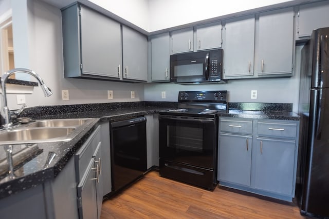 kitchen with light wood-type flooring, gray cabinetry, sink, and black appliances