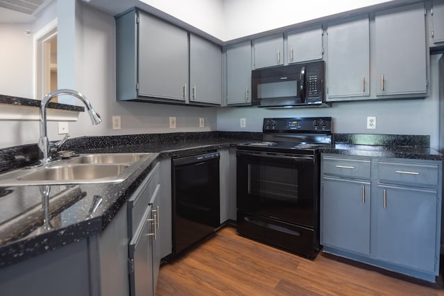 kitchen with hardwood / wood-style floors, gray cabinetry, sink, and black appliances