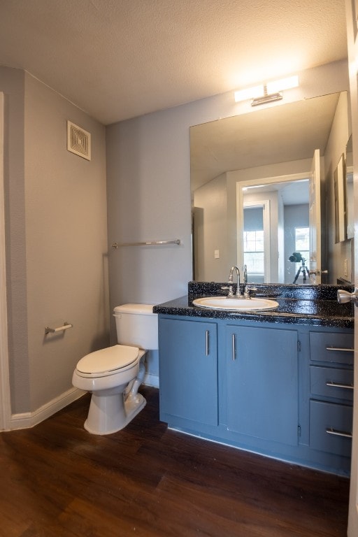 bathroom with wood-type flooring, vanity, toilet, and a textured ceiling