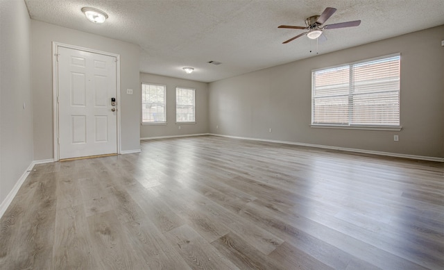 unfurnished room with ceiling fan, a textured ceiling, and light wood-type flooring