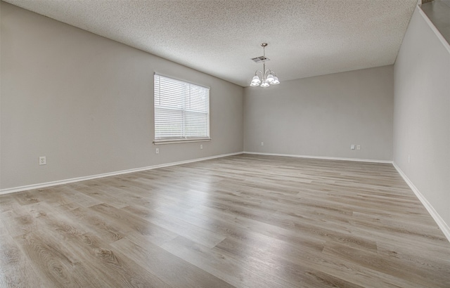 unfurnished room with light wood-type flooring and a textured ceiling