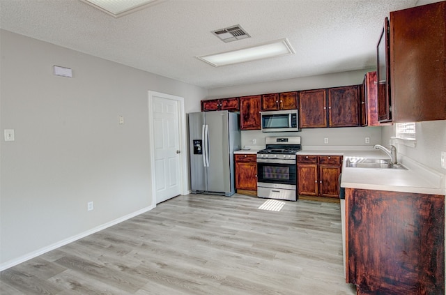 kitchen with light hardwood / wood-style flooring, a textured ceiling, sink, and stainless steel appliances