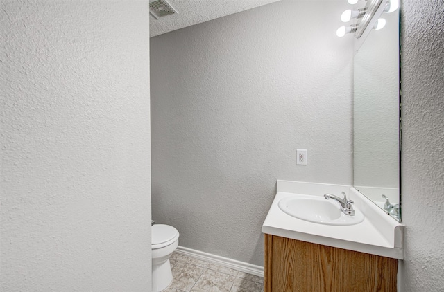 bathroom with tile patterned floors, vanity, toilet, and a textured ceiling