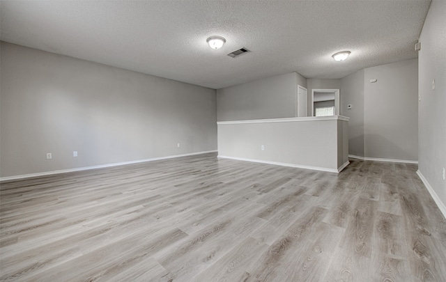 empty room with light wood-type flooring and a textured ceiling