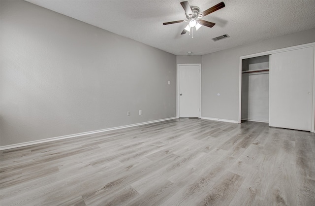 unfurnished bedroom featuring a closet, light hardwood / wood-style floors, a textured ceiling, and ceiling fan